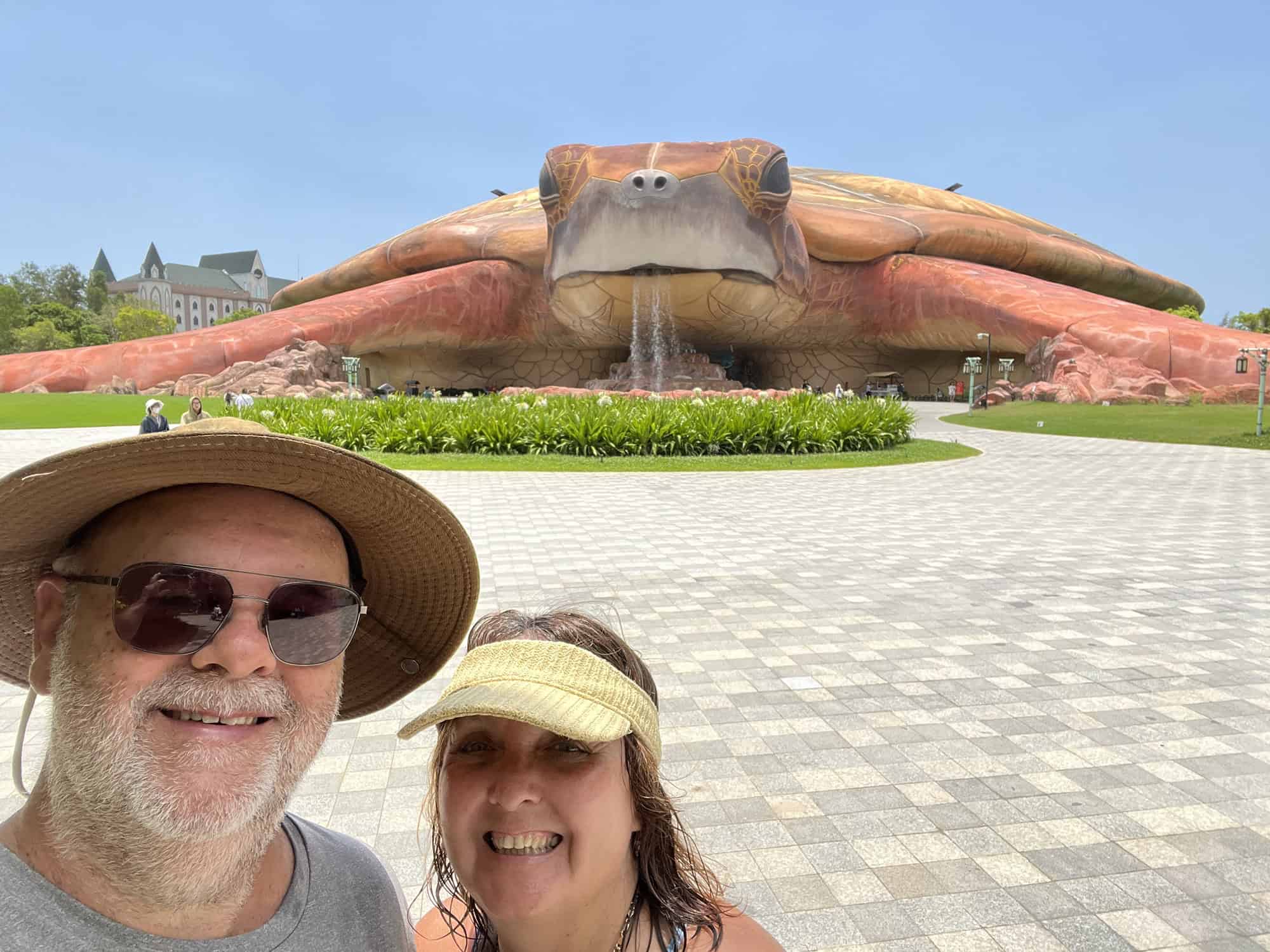 Dean and Pauline from Reasons to Visit stadning in front of the massive turtle-shaped building that houses the aquarium at VinWonders Phu Quoc